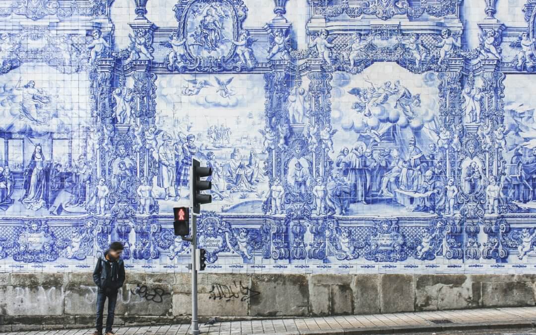 Man at traffic lights in Porto in front of a wall with blue ceramic tiles